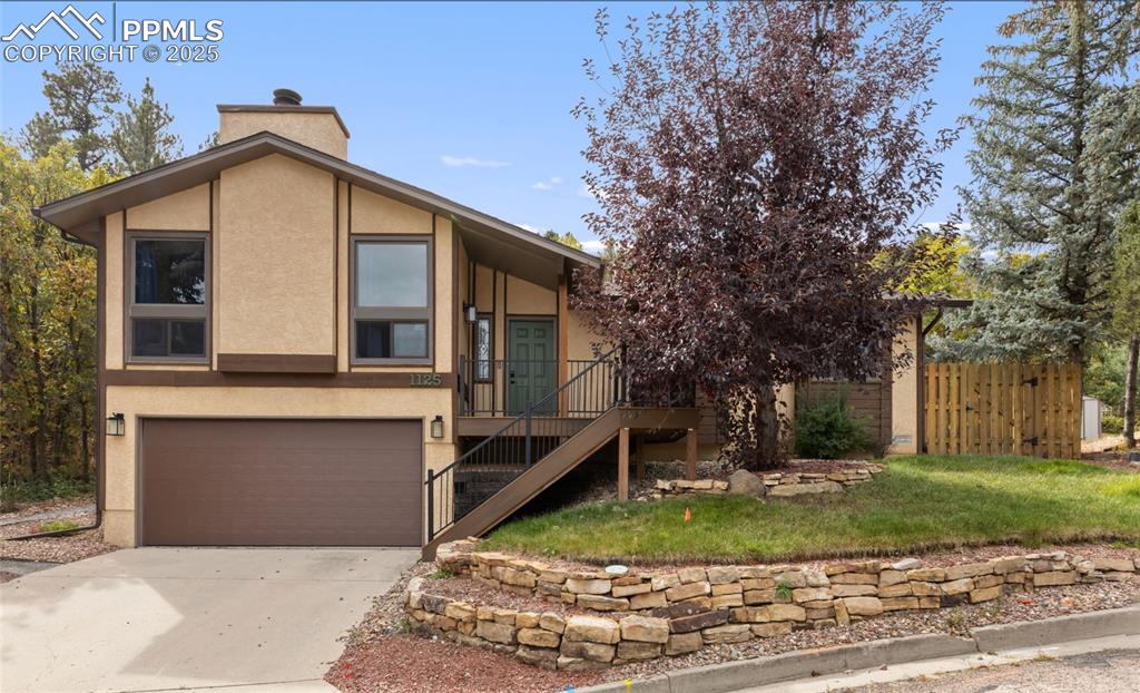 Image 4 of 21: Mid-century home featuring stucco siding, stairs, a garage, and concrete dr