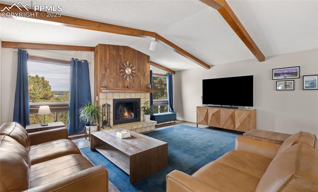 Image 5 of 21: Living room with a textured ceiling, a tiled fireplace, and wood finished f