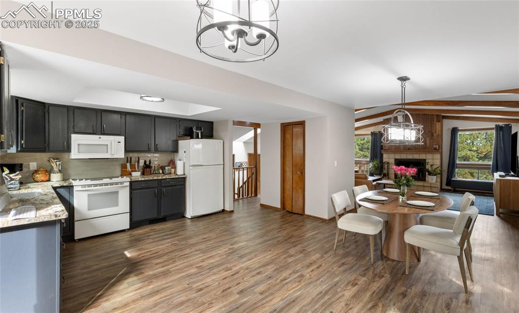 Image 9 of 21: Kitchen featuring white appliances, backsplash, wood finished floors, a cha