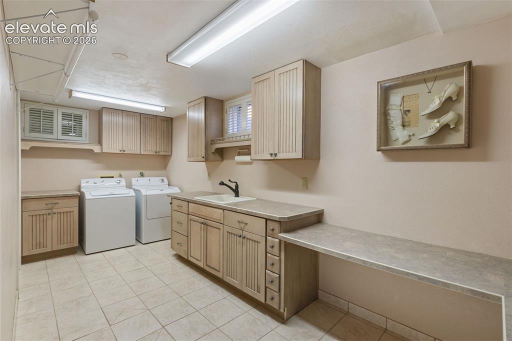 Image 34 of 47: Downstairs laundry with lots of counter space, sink, and windows