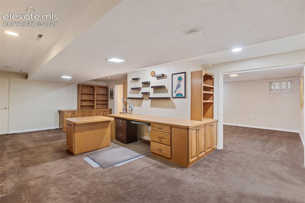 Image 38 of 47: Downstairs office with closets, bookcase, and built-ins