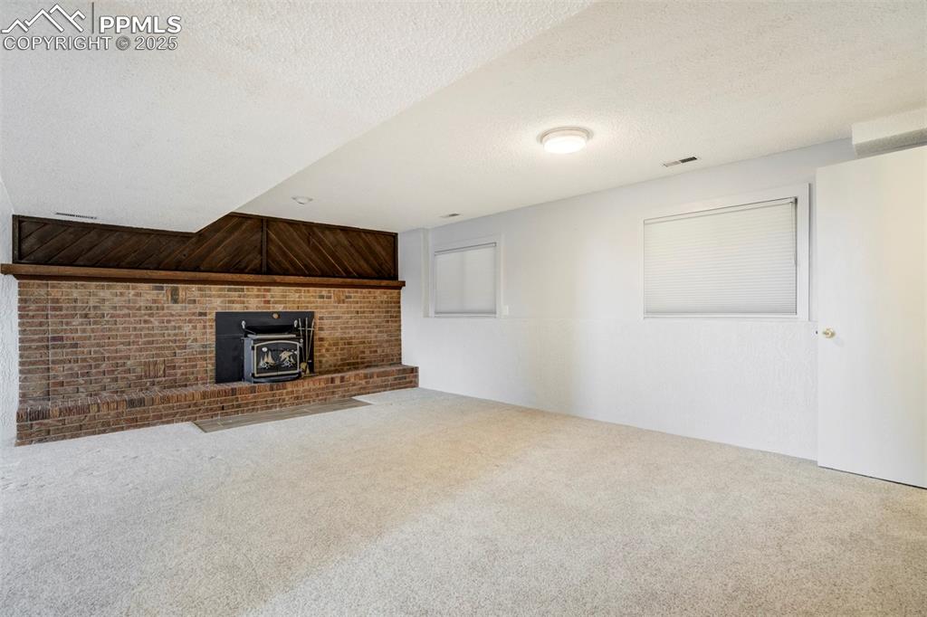 Image 18 of 26: Finished family room in basement with cozy fireplace