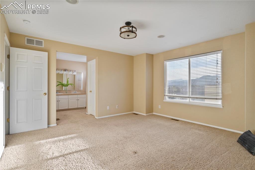 Image 19 of 28: The primary bedroom is spacious and bright with great views.