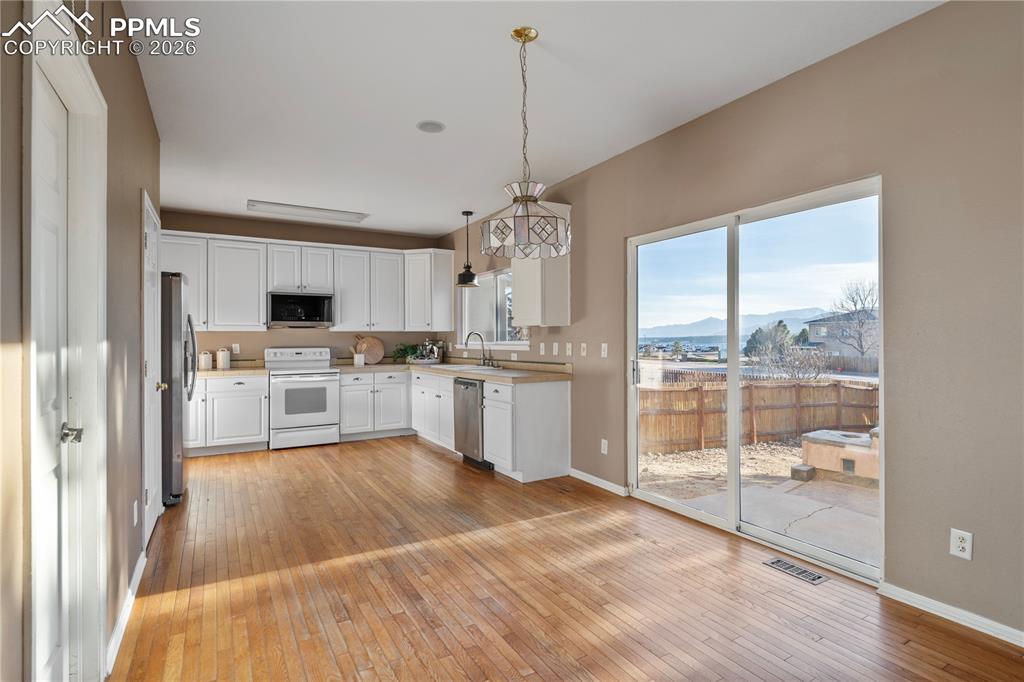 Image 4 of 28: The kitchen has white cabinetry and some updated appliances.