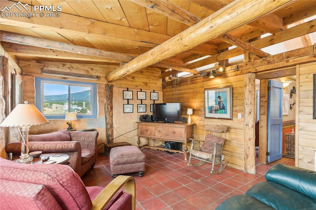 Image 10 of 50: Tiled living area featuring wooden walls and a wooden ceiling with exposed