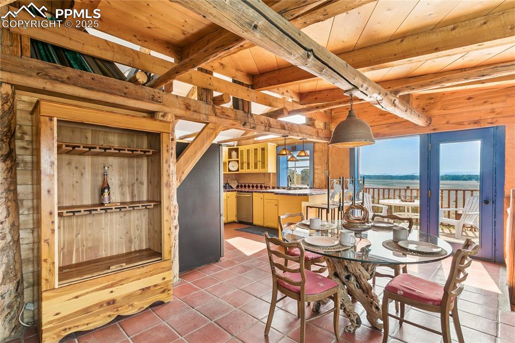 Image 12 of 50: Dining space featuring a wood ceiling with exposed beams, light tile patter