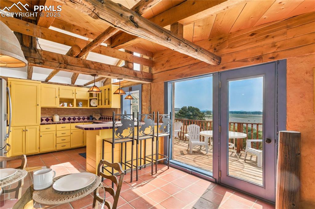 Image 13 of 50: Kitchen with open shelves, a breakfast bar, hanging light fixtures, decorat
