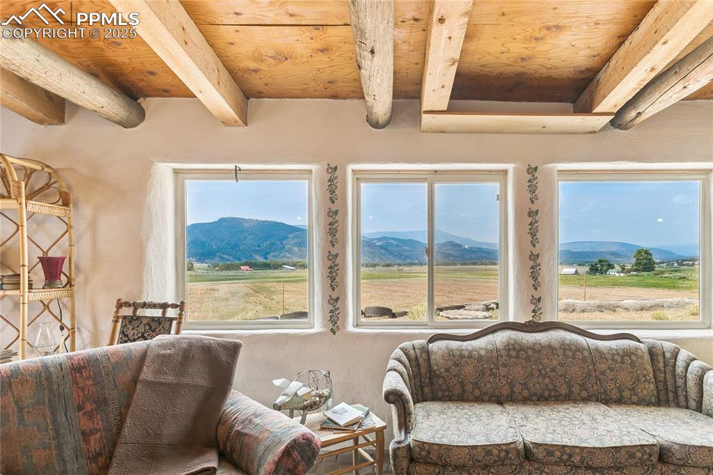 Image 23 of 50: Living area featuring a mountain view and a wooden ceiling with exposed bea