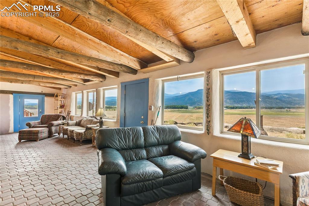 Image 24 of 50: Living room featuring a wooden ceiling with exposed beams and a mountain vi