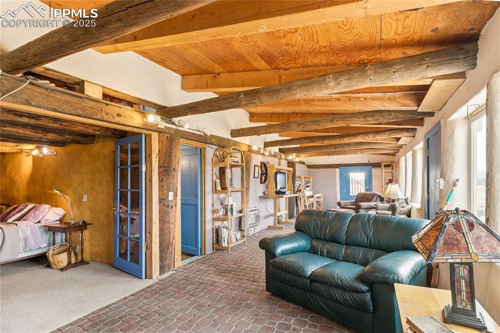 Image 26 of 50: Living room featuring beam ceiling and carpet