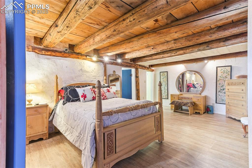 Image 30 of 50: Bedroom with a wooden ceiling with exposed beams and light wood-style floor