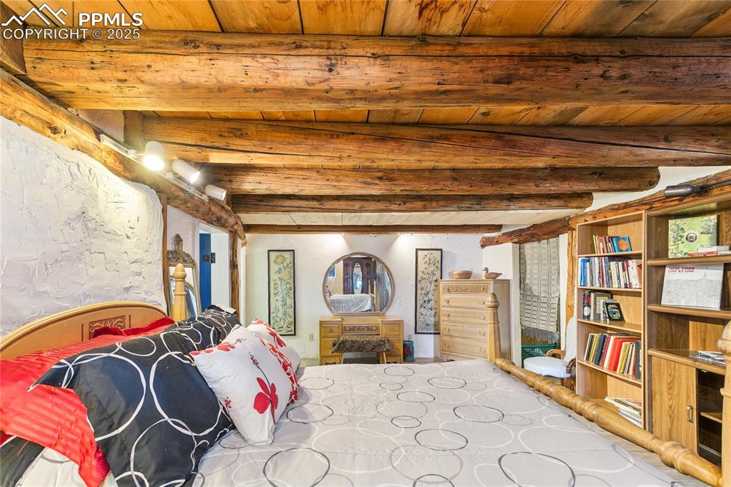 Image 31 of 50: Bedroom featuring a wood ceiling with exposed beams