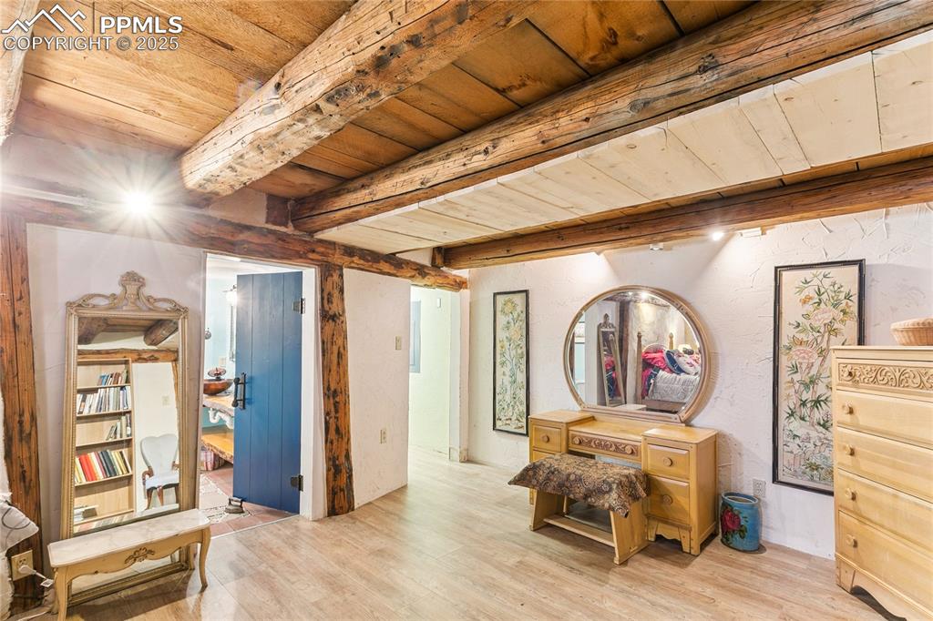 Image 32 of 50: Bedroom with a wood ceiling with exposed beams, wood finished floors, and a