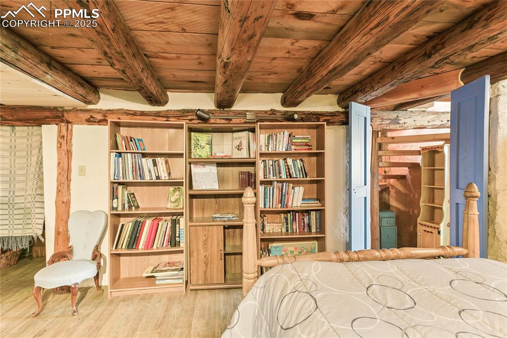 Image 34 of 50: Bedroom featuring light wood-type flooring and a wooden ceiling with expose