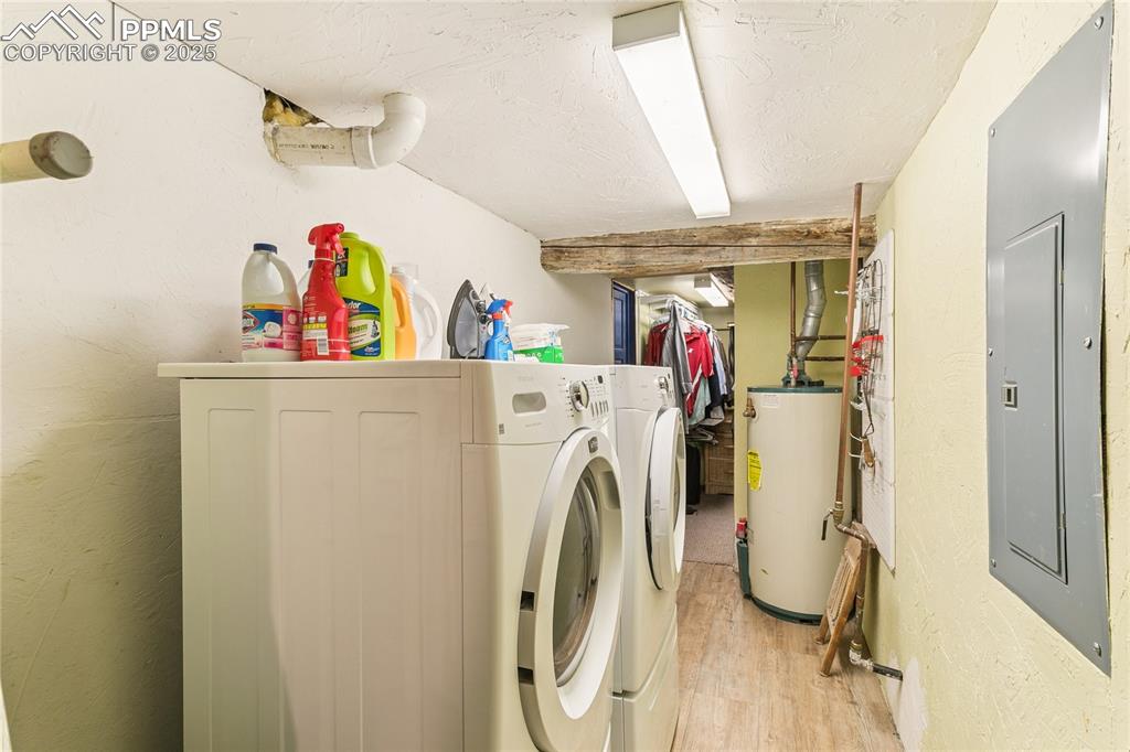 Image 38 of 50: Laundry room with electric panel, gas water heater, washer and dryer, light