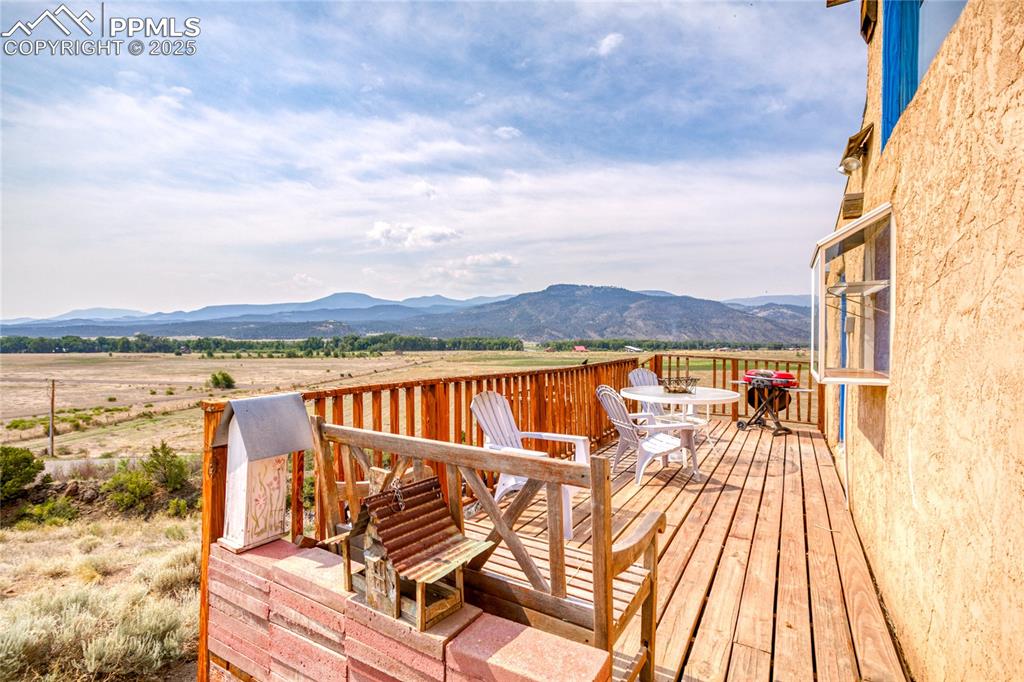 Image 46 of 50: Wooden deck featuring outdoor dining area, a mountain view, and a view of c