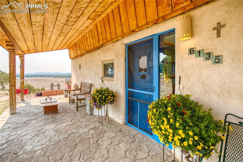 Image 6 of 50: Property entrance with a patio, stucco siding, board and batten siding, and