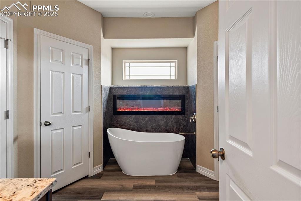 Image 25 of 45: Bathroom with wood finished floors, a freestanding tub, and vanity