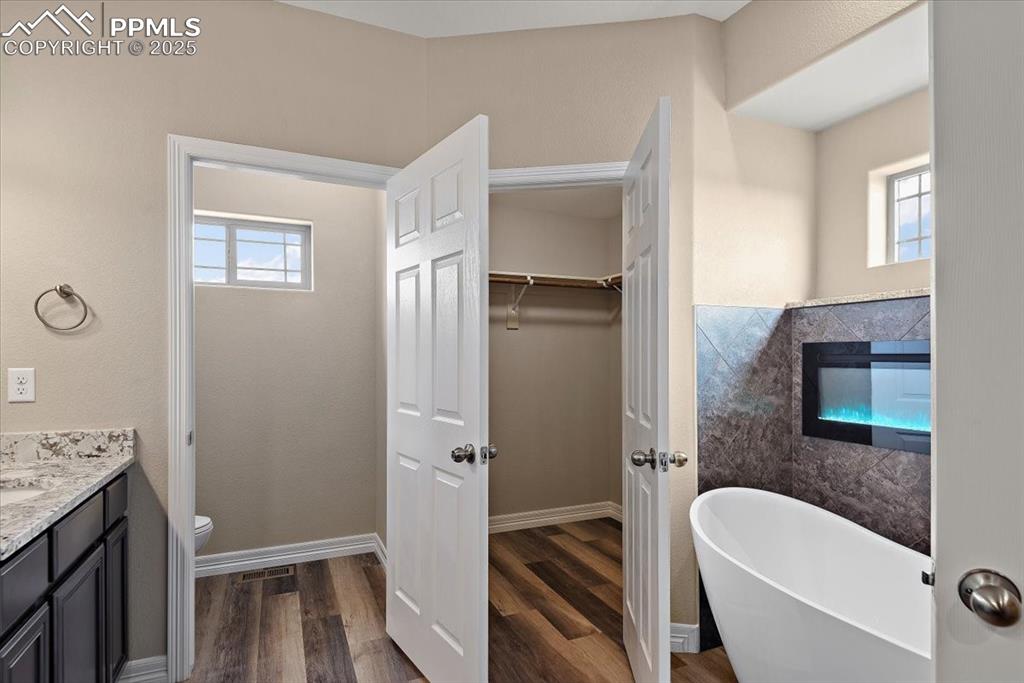 Image 30 of 45: Bathroom with plenty of natural light, vanity, a freestanding bath, and woo