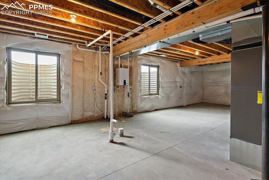 Image 37 of 45: Basement featuring tankless water heater and heating unit