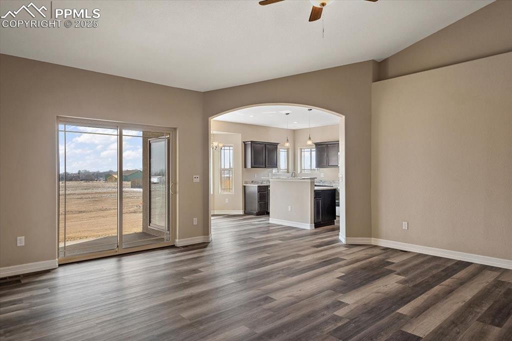 Image 8 of 45: Unfurnished living room with arched walkways, lofted ceiling, dark wood-typ