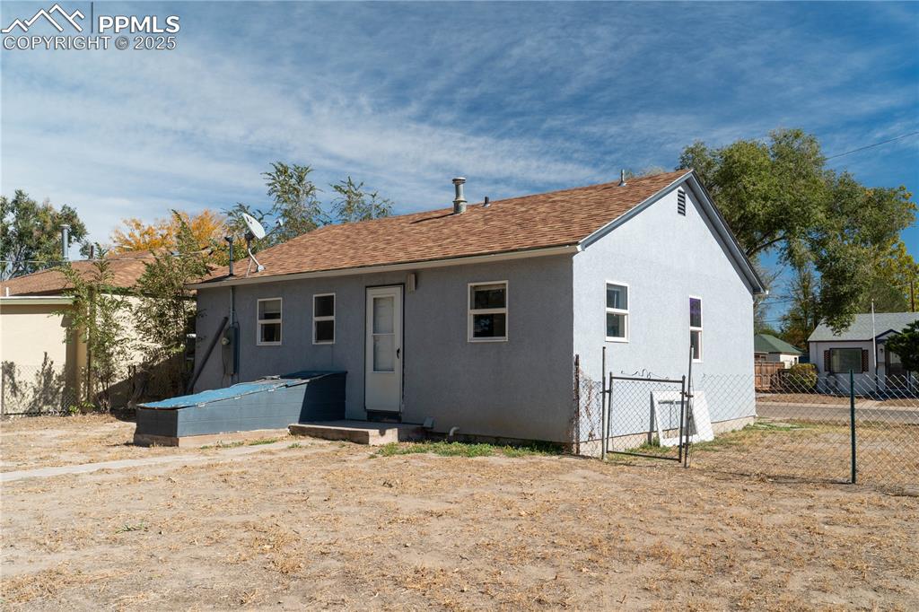 Image 10 of 11: Rear view of property featuring stucco siding and a gate