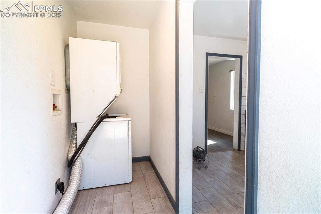 Image 11 of 11: Laundry area with light wood finished floors and stacked washer and clothes