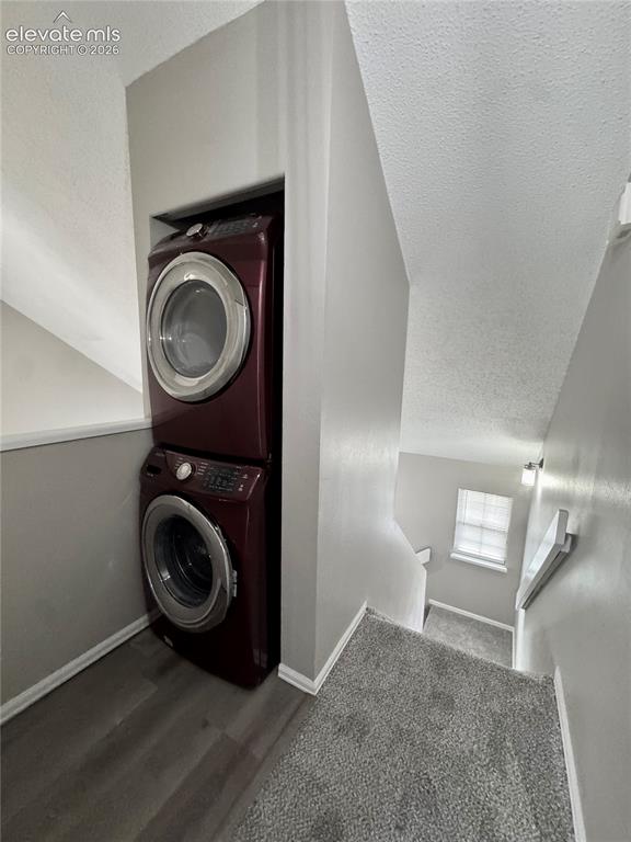 Image 13 of 20: Stackable laundry appliances within an alcove, featuring wood-finish floori