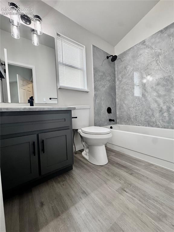 Image 17 of 20: Wood-finish flooring, dark vanity with black hardware, and a tub/shower com