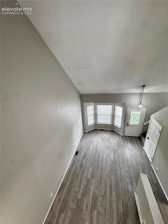 Image 18 of 20: Living area with wood-finish flooring, bay windows, and a hanging pendant l