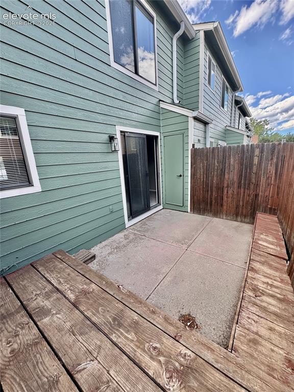 Image 19 of 20: Private patio with concrete slab flooring, a sliding glass door, and a buil