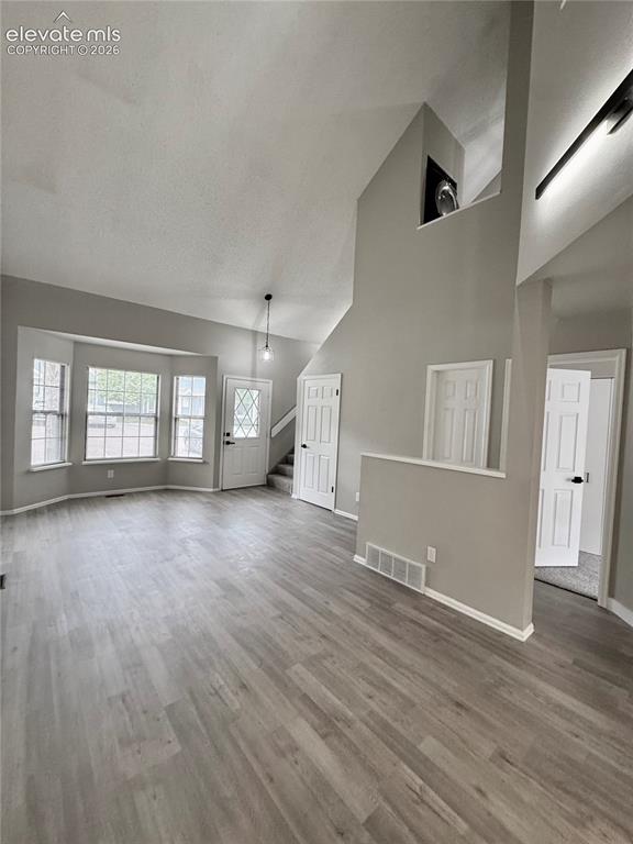 Image 2 of 20: Vaulted ceiling, wood-finish flooring, bay windows, multiple doors, and a d