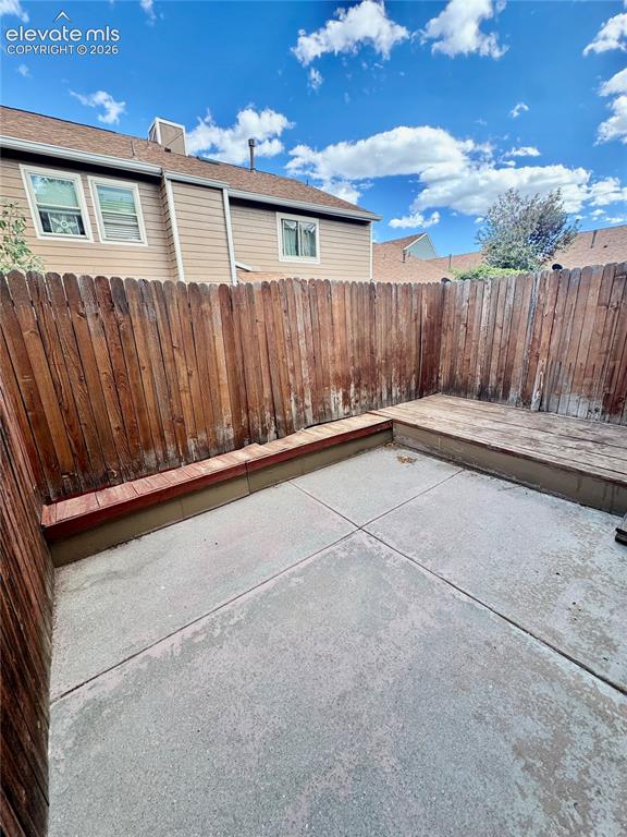 Image 20 of 20: Private outdoor space featuring concrete paving and a raised wooden deck