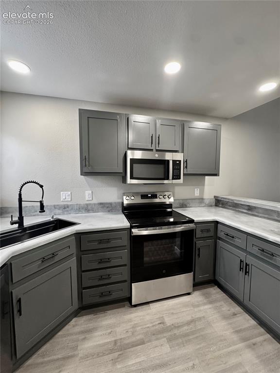 Image 7 of 20: Kitchen featuring gray cabinetry with black hardware, stainless steel appli