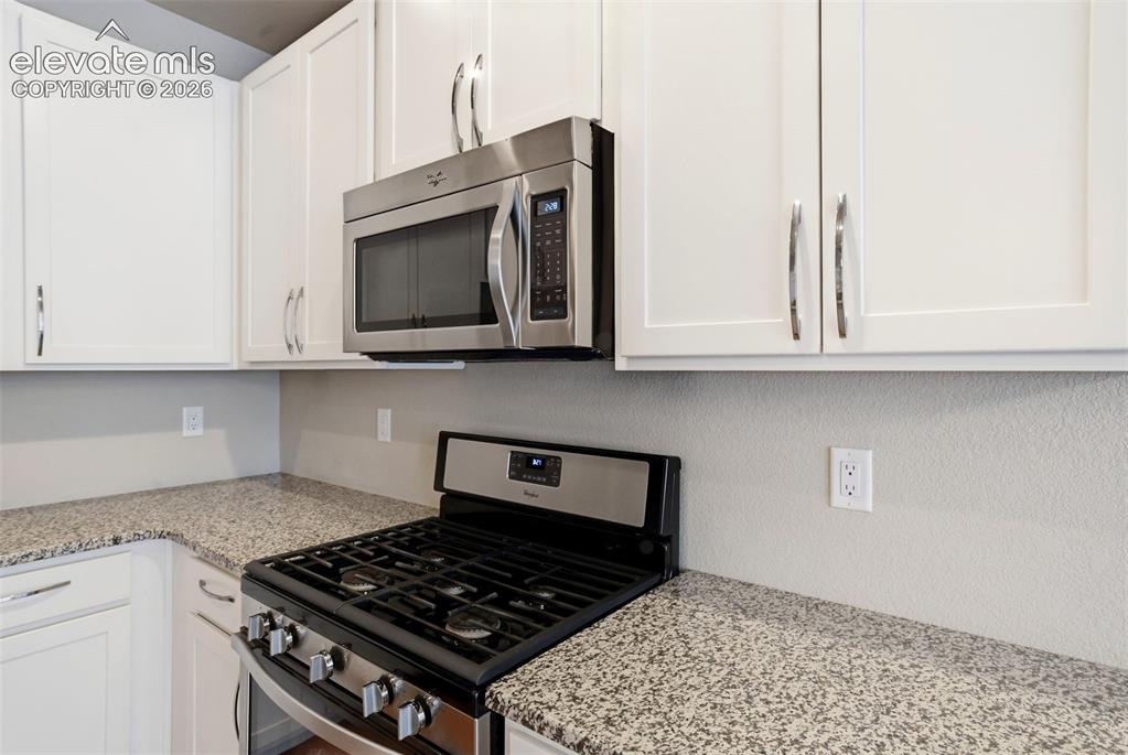 Image 19 of 45: Kitchen featuring gas range and microwave.