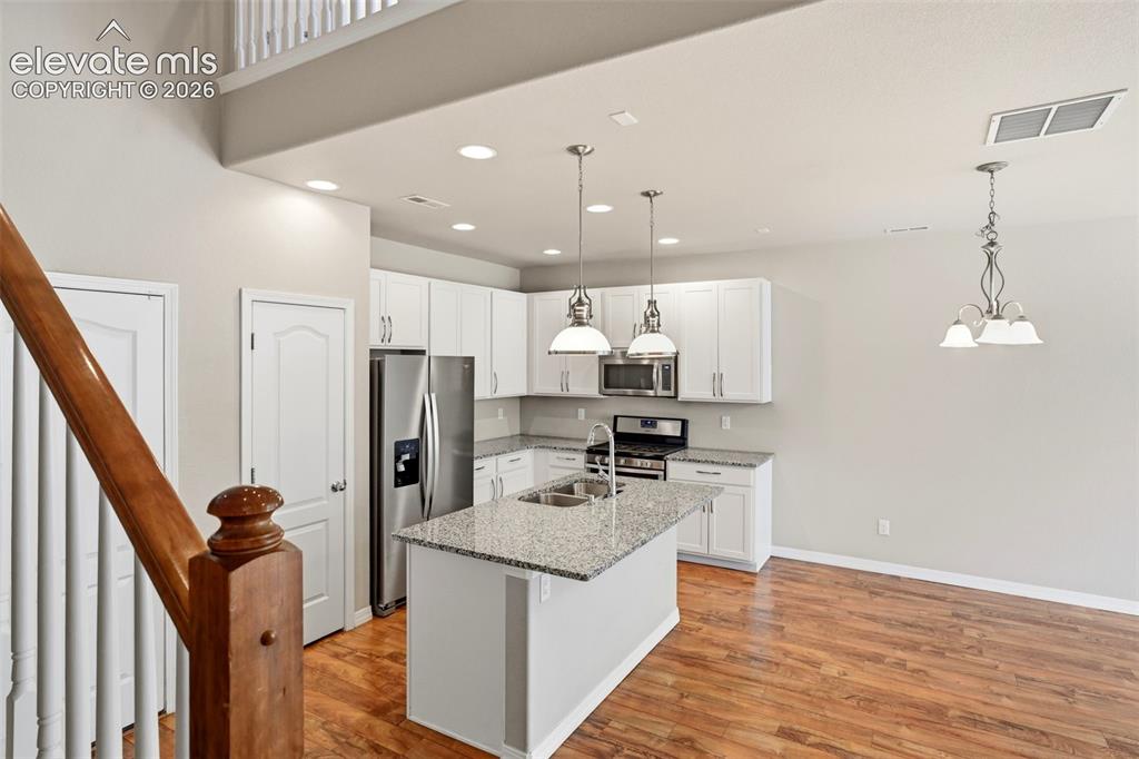 Image 22 of 45: Open-concept kitchen featuring white cabinetry, stainless steel appliances,