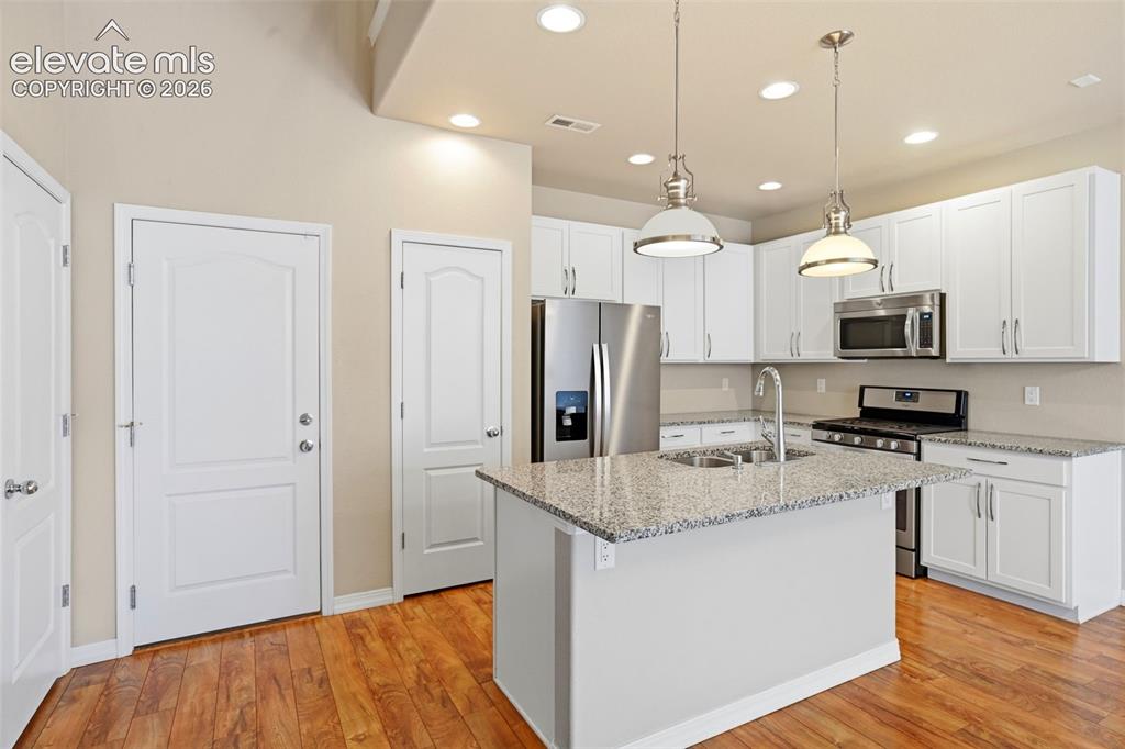 Image 23 of 45: Modern kitchen featuring a central island with granite countertop, stainles