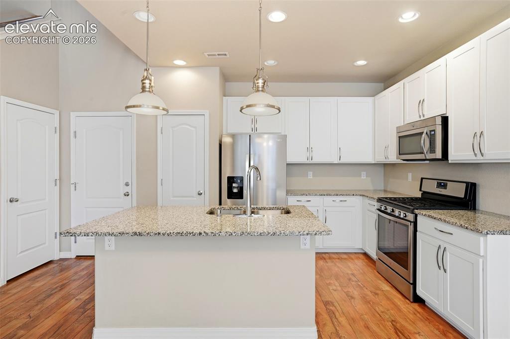 Image 24 of 45: Kitchen featuring a central island with an undermount sink, granite counter
