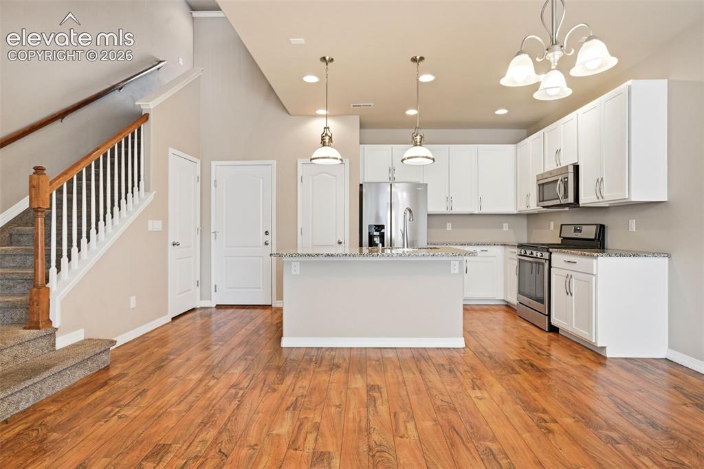 Image 25 of 45: Open-concept living area featuring faux wood-finish flooring, a kitchen isl