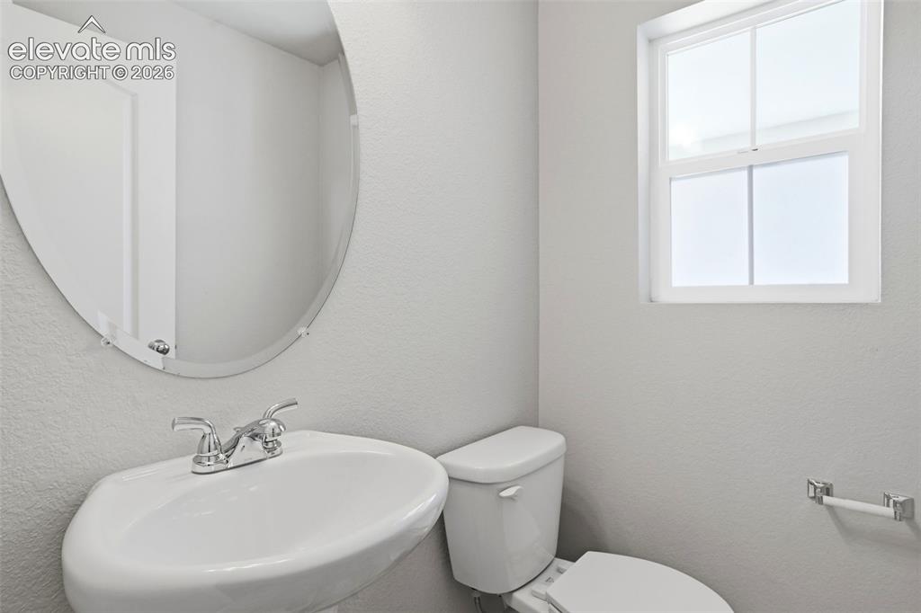 Image 29 of 45: Main Level Powder Bath with Pedestal sink and oval frameless mirror.