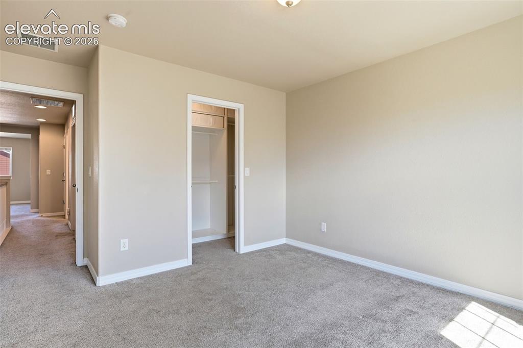 Image 30 of 45: Neutral-toned bedroom featuring plush carpet flooring, a built-in closet wi
