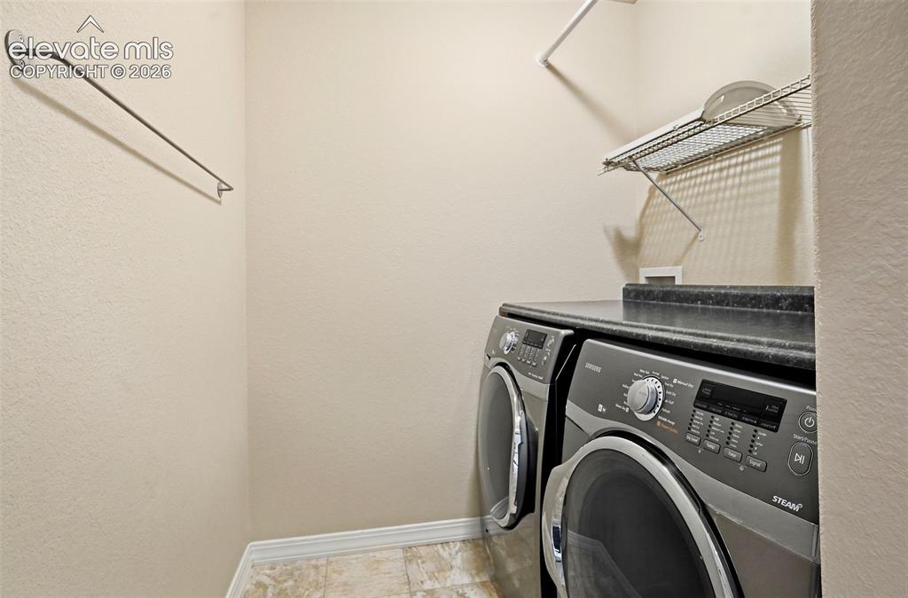 Image 41 of 45: Dedicated laundry area featuring folding counter, upper wire shelving, and 