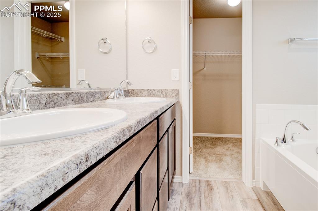 Image 18 of 24: Bathroom featuring a walk in closet, light wood-type flooring, a bath, and 