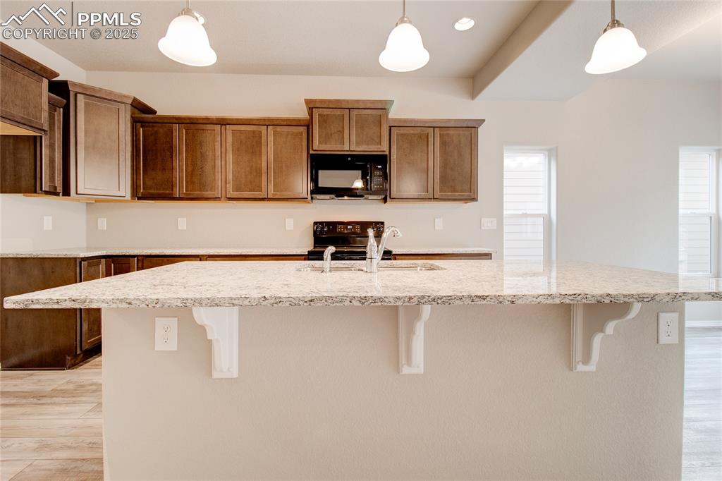 Image 4 of 24: Kitchen with light wood-style flooring, decorative light fixtures, a center