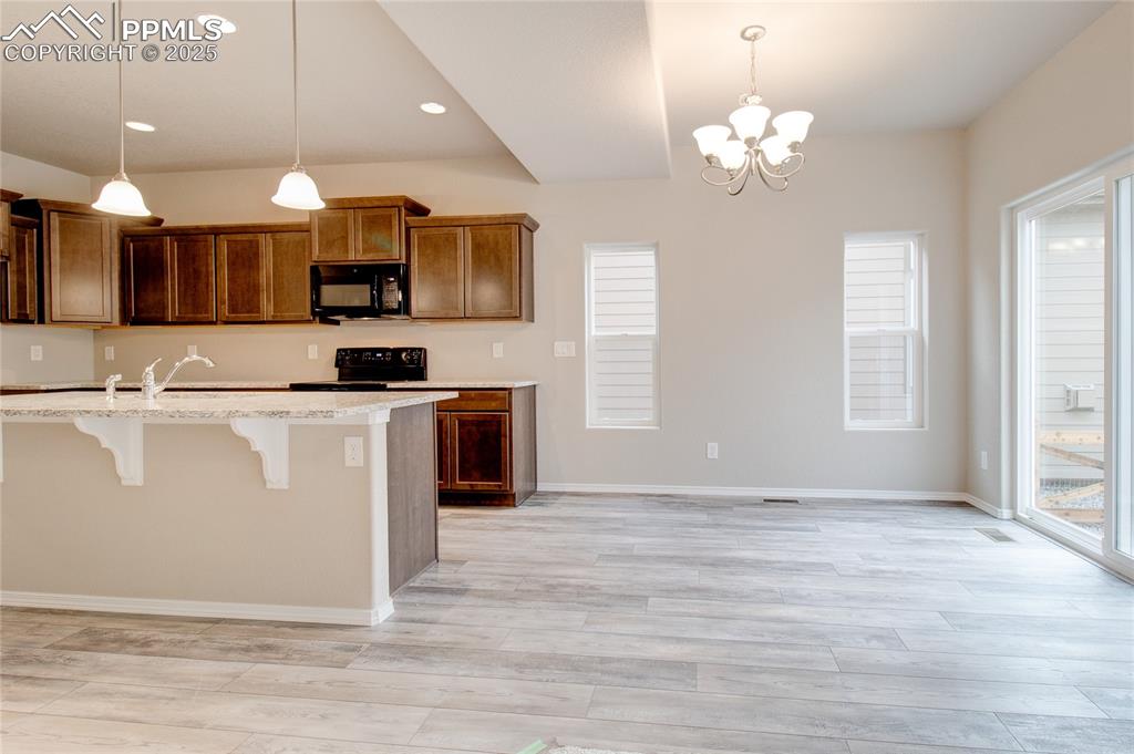 Image 8 of 24: Kitchen featuring a breakfast bar, brown cabinets, light wood finished floo