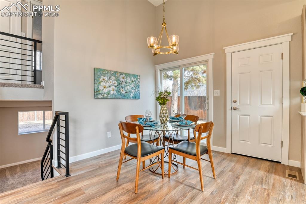 Image 11 of 44: Dining area with a high ceiling, hanging lights, and light wood-style floor