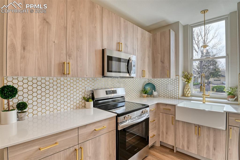 Image 16 of 44: Kitchen with stainless steel appliances, light stone counters, modern cabin
