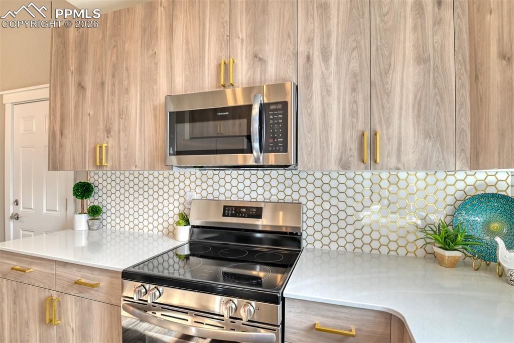 Image 17 of 44: Kitchen with stainless steel appliances, backsplash, modern cabinets, and l