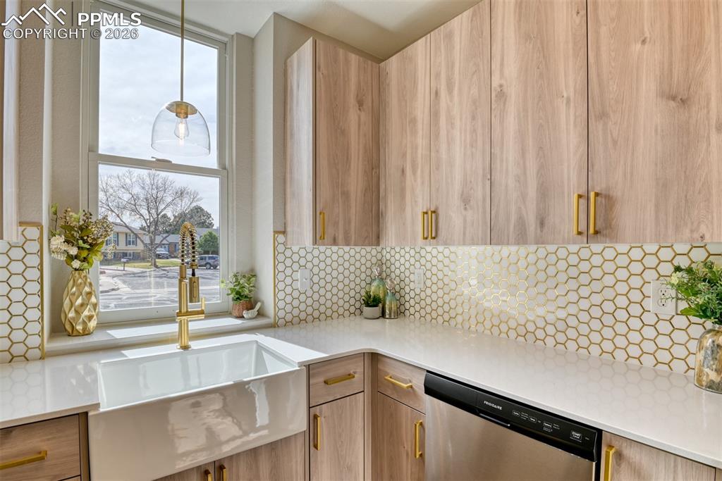 Image 18 of 44: Kitchen with modern cabinets, dishwasher, light stone countertops, light wo