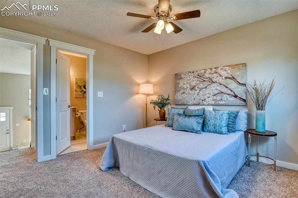 Image 20 of 44: Bedroom with a textured ceiling, light colored carpet, and a ceiling fan